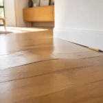 Un parquet flottant qui bombe au milieu du salon révèle presque toujours un manque de jeu le long des murs plutôt qu’un défaut au centre